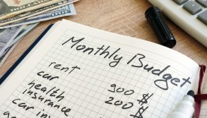 Note pad with monthly budget calculations and money.